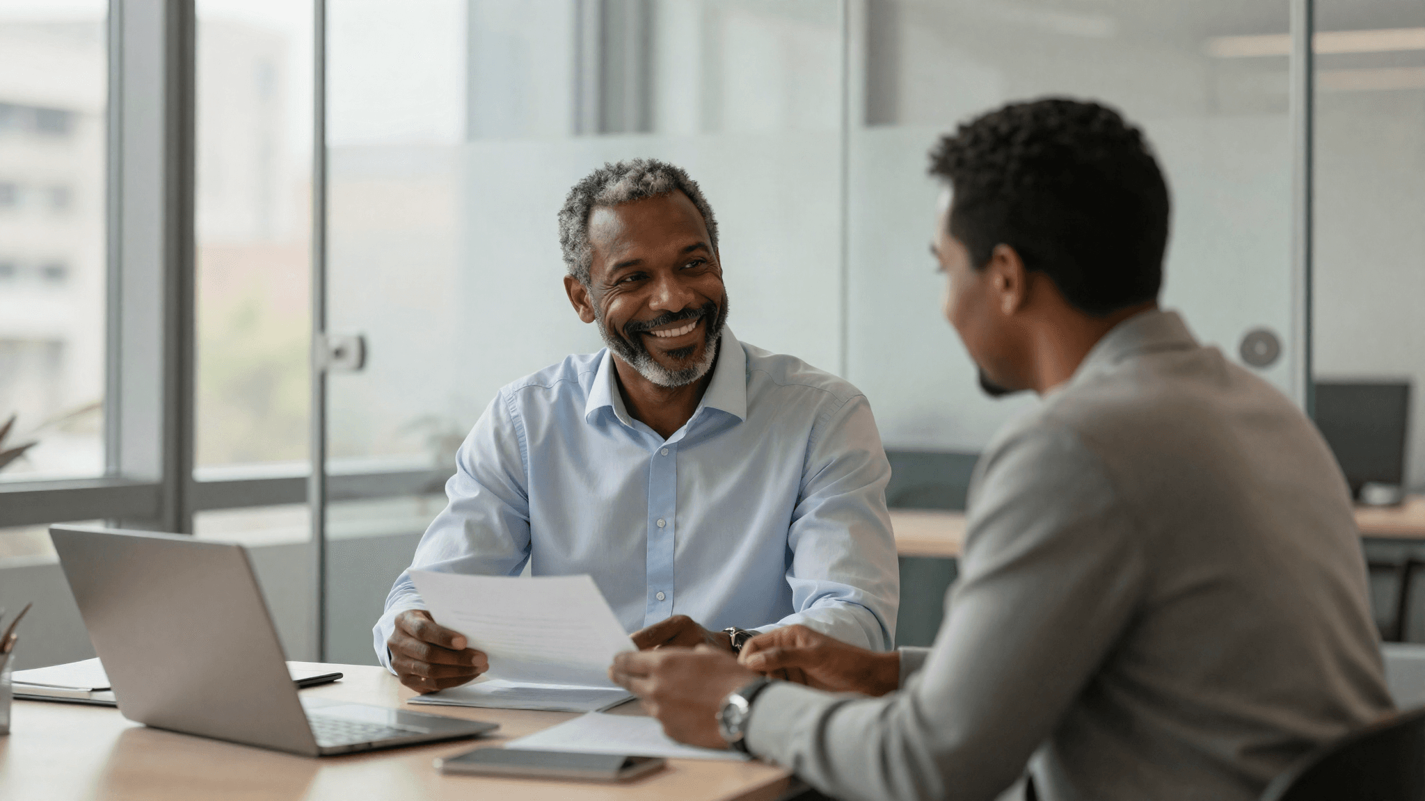 A business banker in warm conversation with a client at a glass-walled office